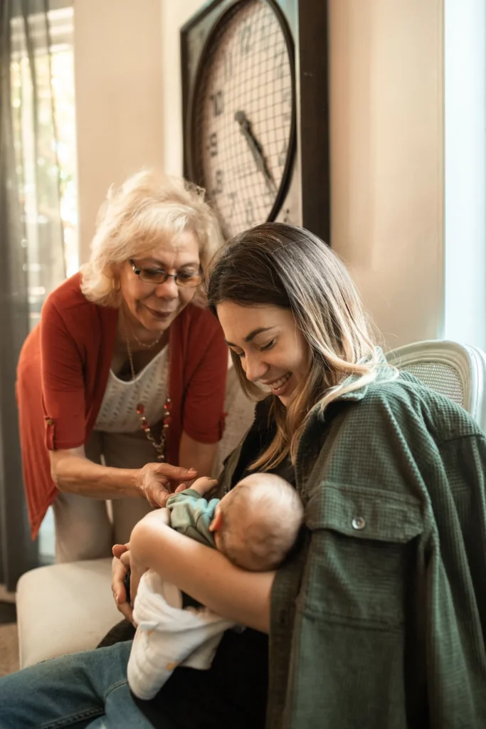 Grandmother and granddaughter, with the granddaughter's baby all in a household living room.