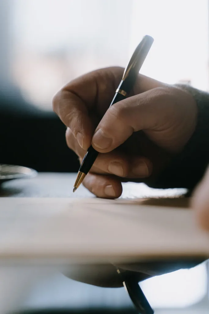 Hand signing a document with a pen